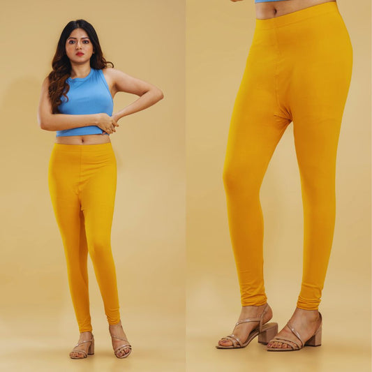 Woman wearing yellow leggings with a plain background