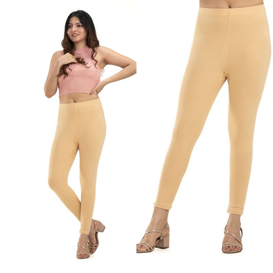 Woman wearing beige leggings with a plain background