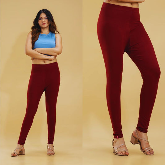 Woman wearing maroon leggings with a plain background