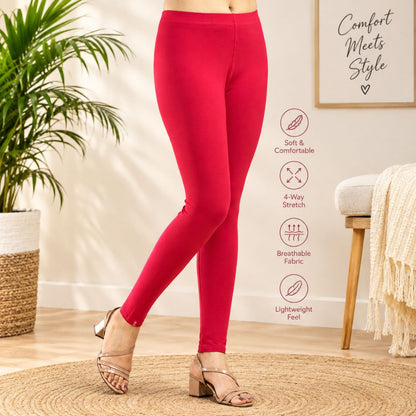 A person wearing bright red full-length leggings and heeled sandals in a styled indoor room with a plant, framed wall art, chair, and woven rug. Text callouts on the right describe soft comfort, stretch, breathable fabric, and lightweight feel.