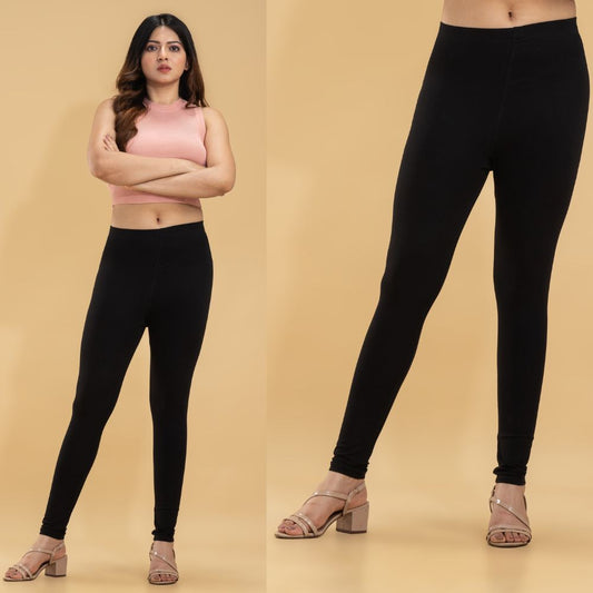 Woman wearing black leggings and a pink crop top on a beige background