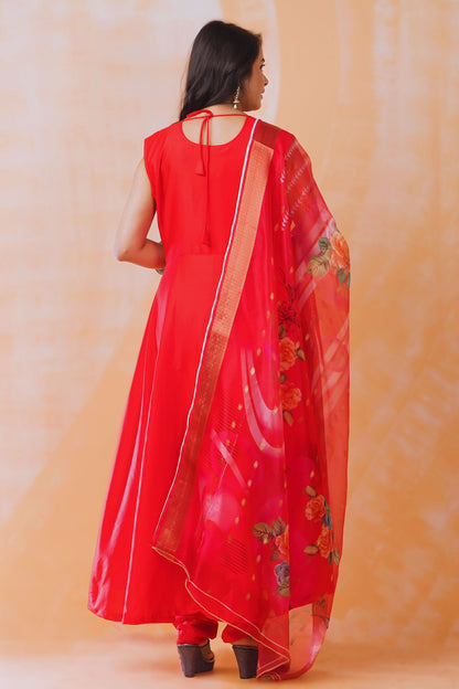 Woman wearing a red traditional outfit with a matching dupatta against an orange background