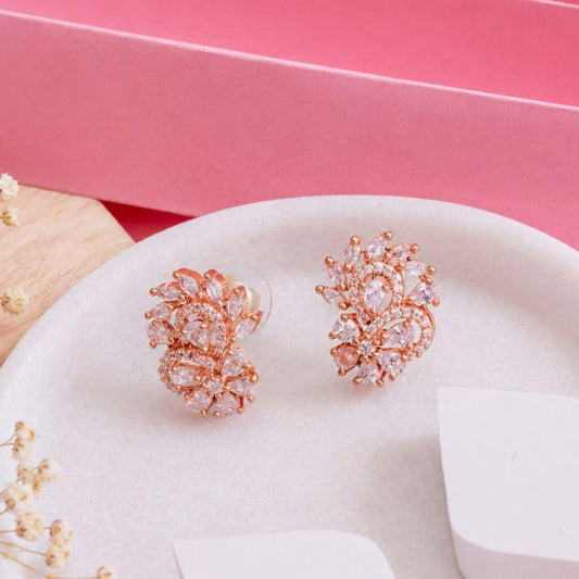Rose gold floral stud earrings with clear marquise-cut crystals, displayed on a white oval tray with a pink background.