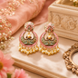 Ornate earrings with pearl details on a decorative surface with flowers and a box.