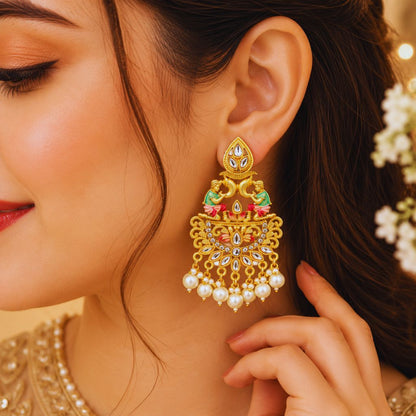 A close-up portrait of a woman wearing an ornate traditional gold-plated chandelier earring with colorful detailing and multiple pearl drops, showcasing the intricate ethnic design.