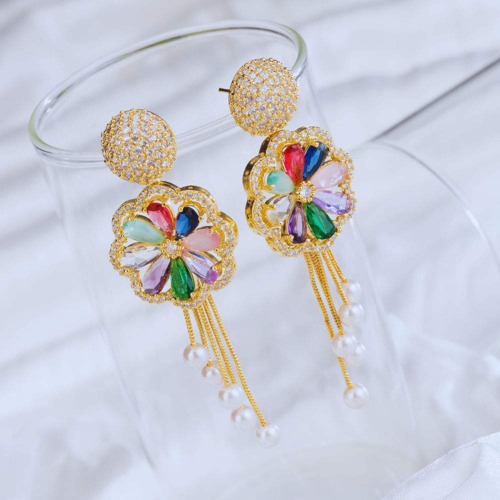Colorful earrings with gold frames and gemstones on a white fabric background