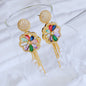 Colorful earrings with gold frames and gemstones on a white fabric background