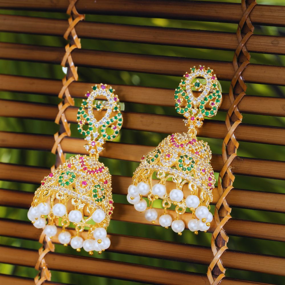Ornate earrings with pearls and gemstones on a woven surface