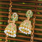 Ornate earrings with pearls and gemstones on a woven surface