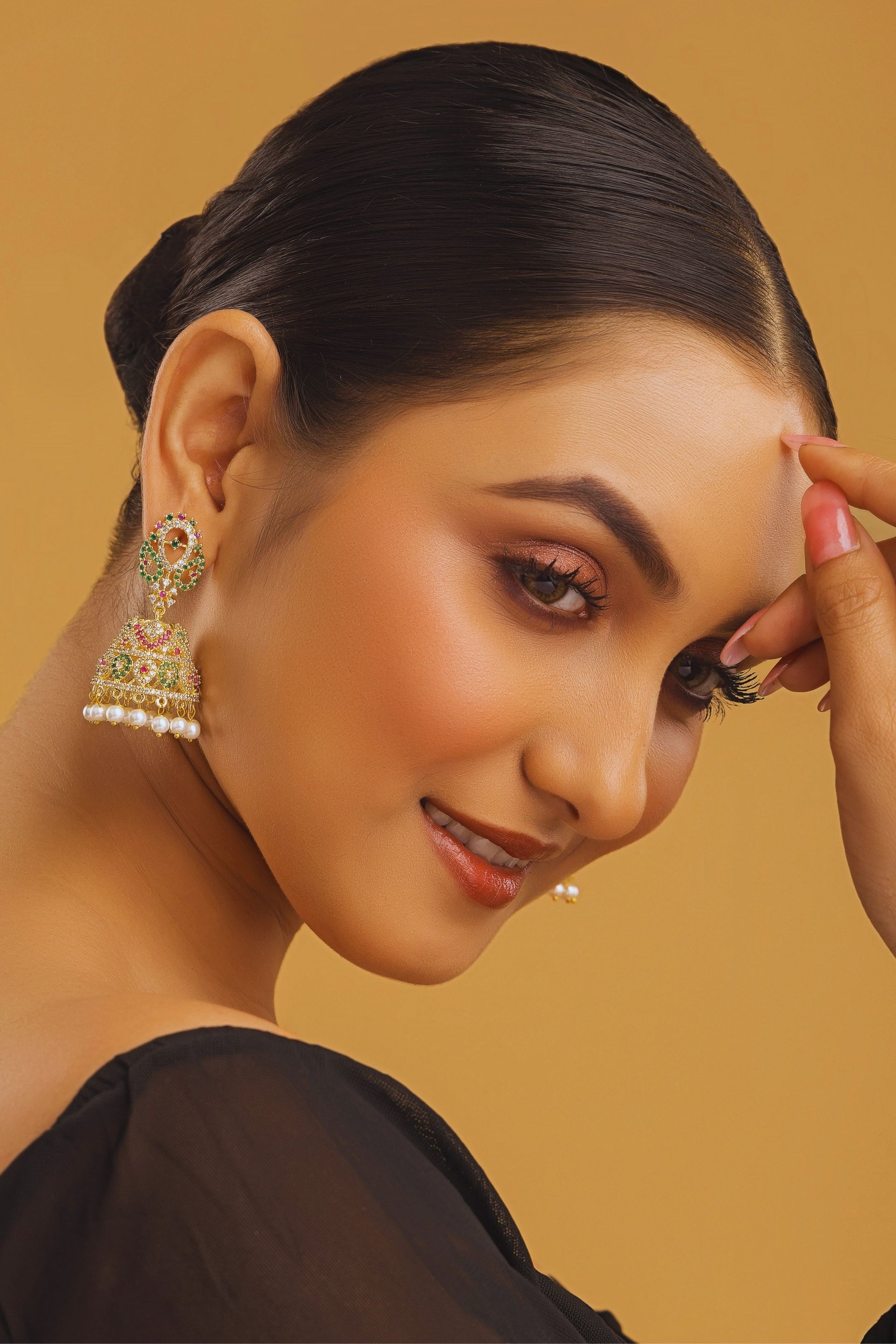 Woman wearing gold earrings with a beige background