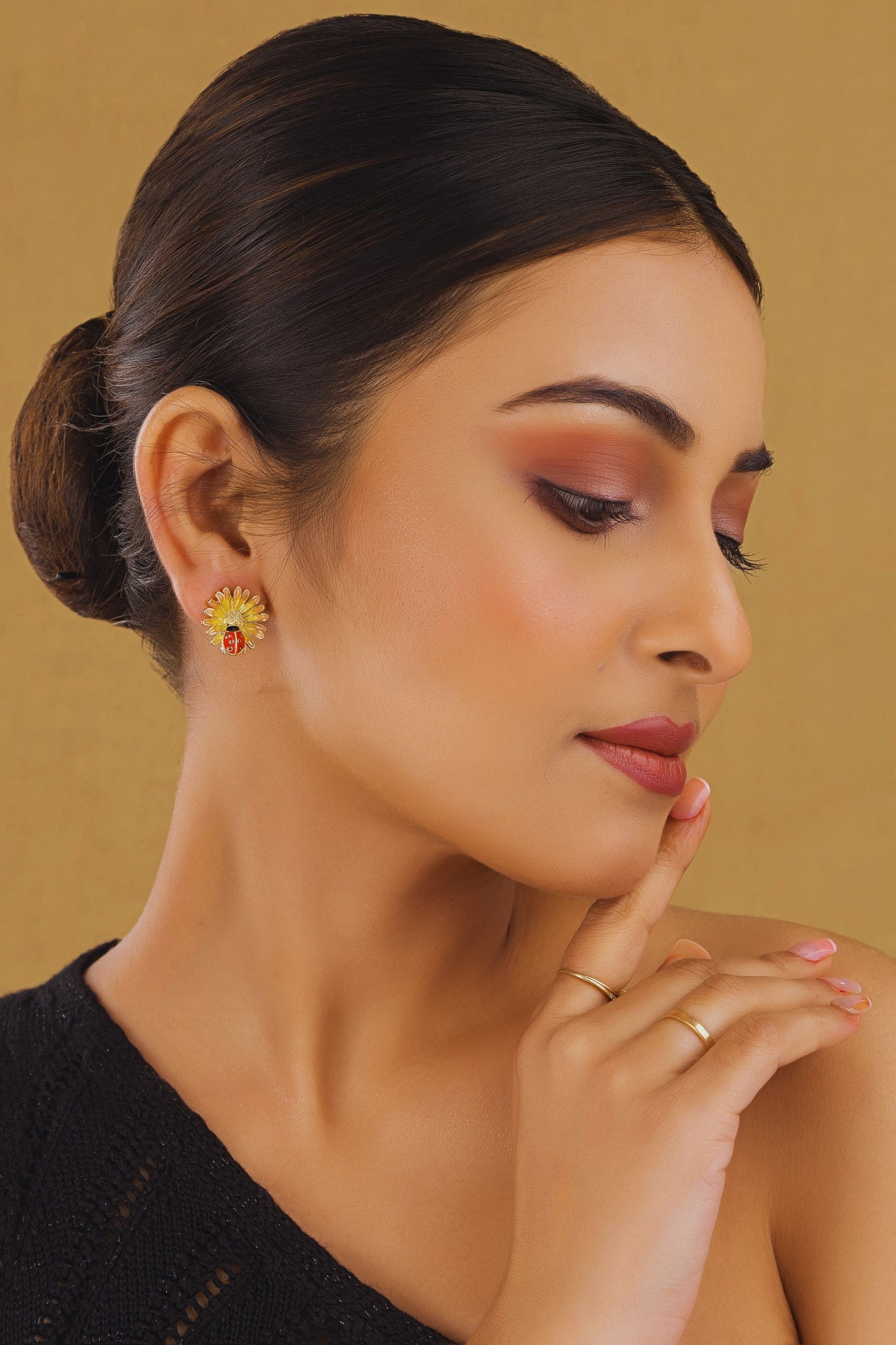 Woman wearing sunflower earrings with a beige background