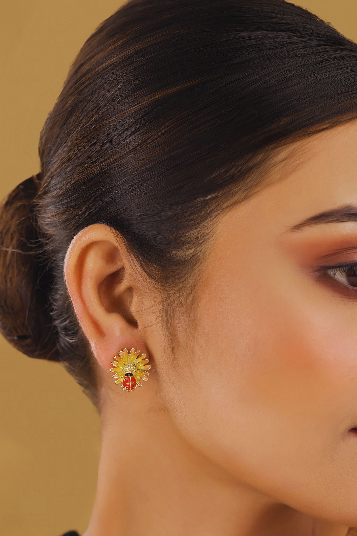Close-up of a woman wearing a floral earring against a beige background
