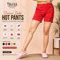 A model wearing bright red hot pants with decorative buttons and pink slip-on shoes, shown in a styled indoor setting with promotional text and icons for Tito's Fashion House.