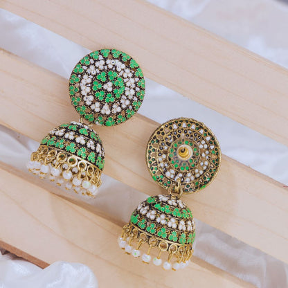 Ornate earrings with green and gold details on a wooden surface
