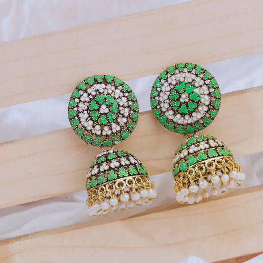 Pair of green and gold earrings on a wooden surface
