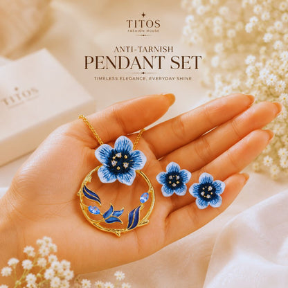 Floral pendant set held in a hand with 'TITOS' branding
