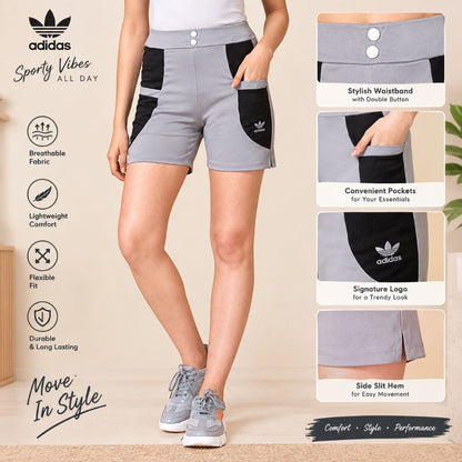 A model wears gray and black Adidas Sporty Vibes athletic shorts with a side slit hem, double-button waistband, and pockets. The image includes feature callout panels and text highlighting breathable fabric, lightweight comfort, flexible fit, and durable long-lasting performance.