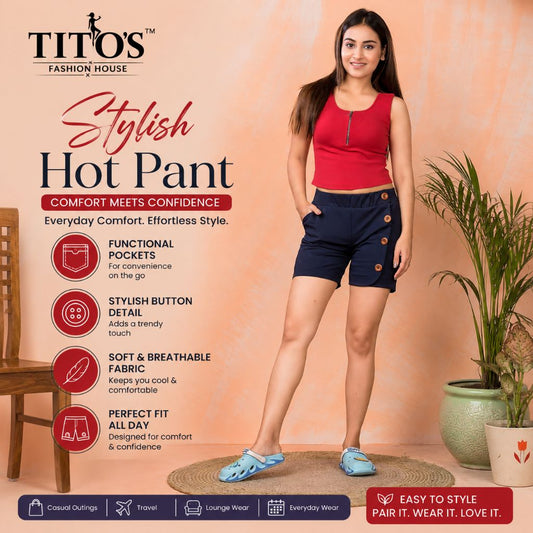 A woman modeling a pair of dark navy blue hot pants with decorative gold buttons, styled with a red sleeveless top and blue slide sandals. The image is a promotional graphic for 'TITO'S Fashion House' styled Hot Pant, featuring product details on the left and a potted plant on the right against a peach-colored background.