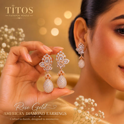 Rose gold American diamond earrings being held by a hand with a blurred background featuring 'TITOS Fashion House'.