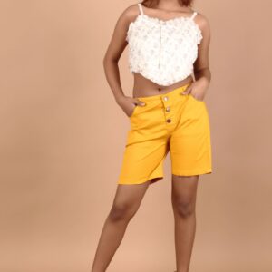 Girl wearing mustard short pant and standing with her hands in her both pockets with innocent face