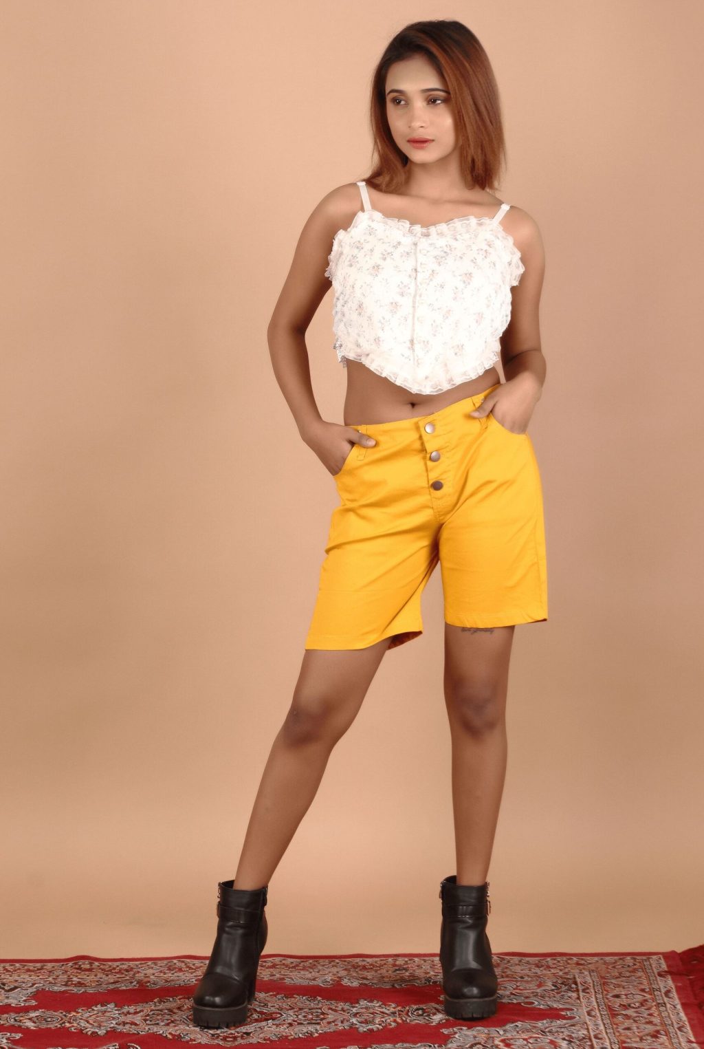 Girl wearing mustard short pant and standing with her hands in her both pockets with innocent face